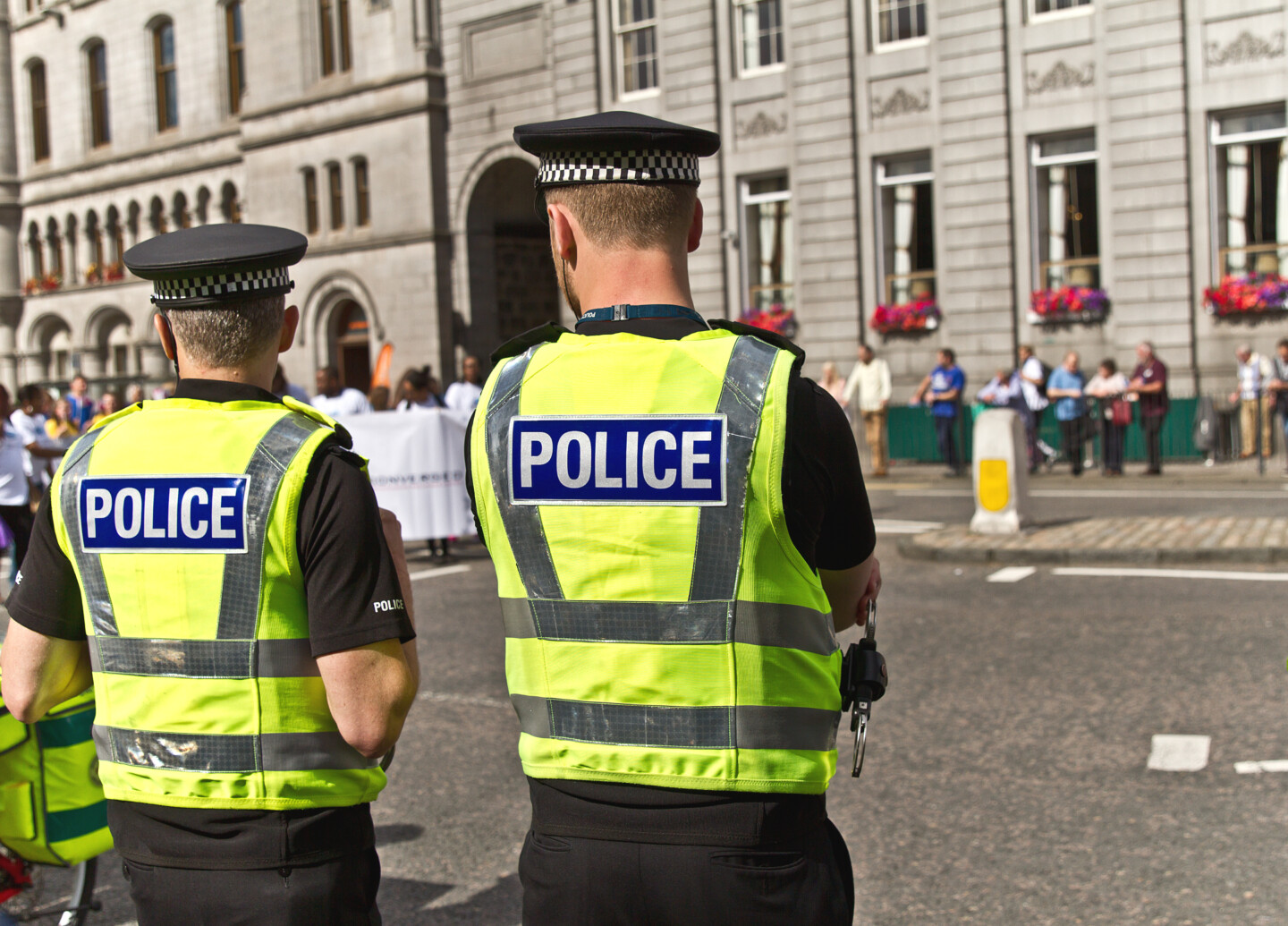 Two,Police,Officers,In,Uniform,Watching,The,Crowd